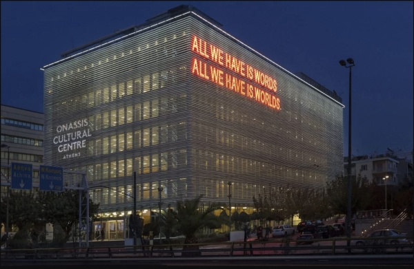 The Onassis Cultural Center with "ALL WE HAVE IS WORDS. ALL WE HAVE IS WORLDS." illuminated in red