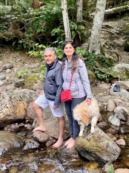 Neeraj (left), his wife, and dog on a hike in the mountains around Seattle, in a rocky stream near a forest