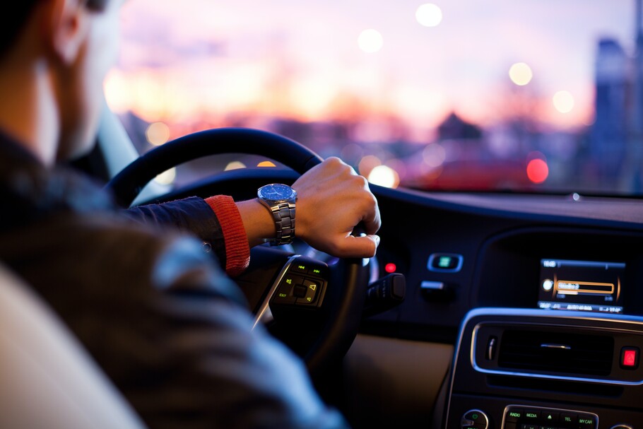 A man is shown driving a car as if the viewer is in the back seat.